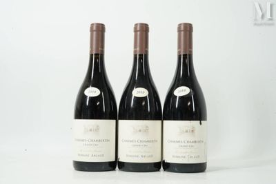 trois bouteilles de vin sont alignées sur une surface blanche