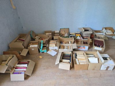 de nombreuses caisses de livres posées par terre dans une pièce