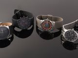three different watches sitting on top of a black surface