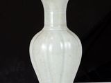 a white vase sitting on a table with a black background