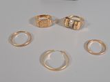 several gold rings and a ring with a diamond on a white surface