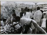 une photo en noir et blanc montrant un groupe de personnes réunies autour d'une table