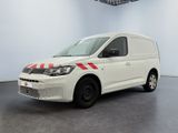 La camionnette blanche est garée dans une pièce blanche ; elle porte une bande rouge sur le côté.