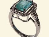 an image of a ring with a green stone surrounded by diamonds