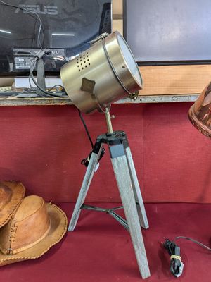 une lampe posée sur un trépied à côté d'un chapeau