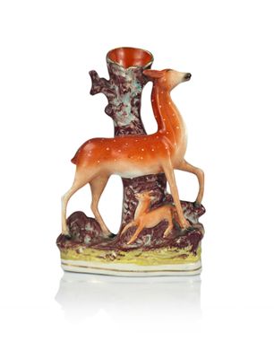 a figurine of a deer and a deer on a tree stump