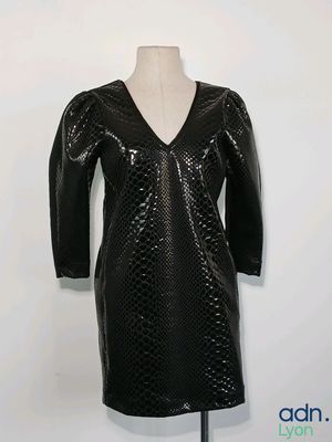 La robe est noire, avec un col en V et des manches longues.