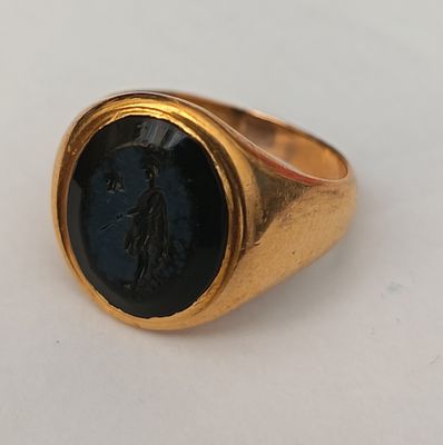 an image of a gold signet ring with a black stone in the center