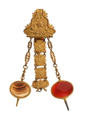une image représentant une broche dorée et rouge suspendue à une chaîne