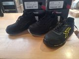 Deux paires de chaussures noires et jaunes sont posées sur une table en bois.