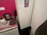 a small kitchen with a white refrigerator and a pink wall