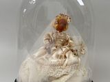 une figurine représentant une femme en robe de mariée, placée sous un dôme en verre