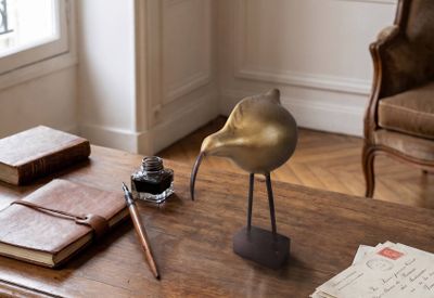 une statue d'oiseau posée sur une table, à côté d'un livre