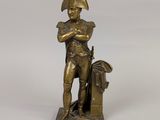 an antique bronze statue of a man with a hat and a bag
