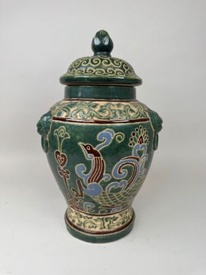 un vase vert orné d'un oiseau sur fond blanc