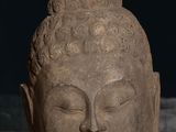 statue of a head of a buddha on a table with a dark background