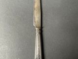 a silver knife on a black surface with a silver handle