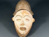 a close up of a wooden mask on a black background