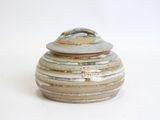 a ceramic jar with a lid on a white surface