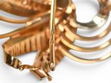 a close up of a gold brooch on a white surface