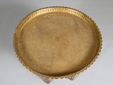 a gold tray on a stand on a white surface