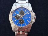 a close up of a watch with a blue face on a black surface