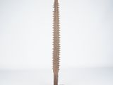 une sculpture en bois représentant une grande vis posée sur un socle métallique