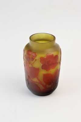 a yellow vase with red flowers on it on a white surface
