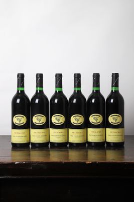six bouteilles de vin sont posées sur une table devant un mur blanc