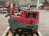 une machine rouge posée sur une palette dans un entrepôt