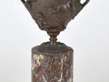 une image représentant un trophée en bronze posé sur un socle en marbre