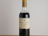 une bouteille de vin rouge posée sur une table en bois, avec un mur blanc en arrière-plan