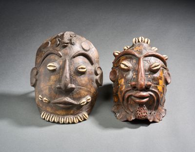 une paire de masques en bois sculpté sur un fond gris