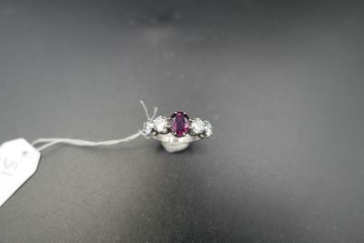 a close up of a white gold ring with a pink stone
