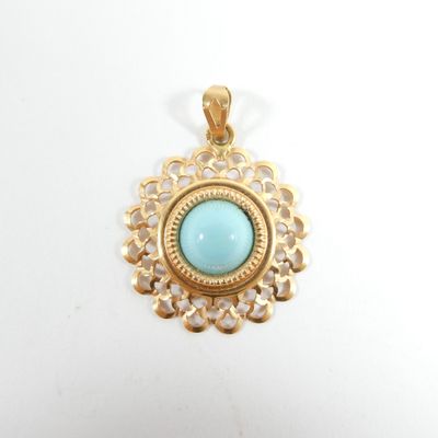a close up of a gold pendant with a turquoise stone