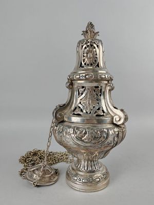 un vase en argent richement décoré, d'une chaîne suspendue à son col