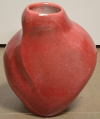 un vase rouge accroché au mur, à côté d'un mur blanc