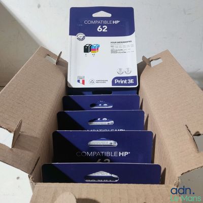 Quatre cartouches d'encre se trouvent dans une boîte en carton posée sur une table