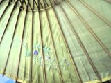 un gros plan sur un parapluie vert avec un ciel bleu en arrière-plan