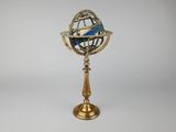 une image représentant un petit globe terrestre posé sur un socle, sur fond blanc