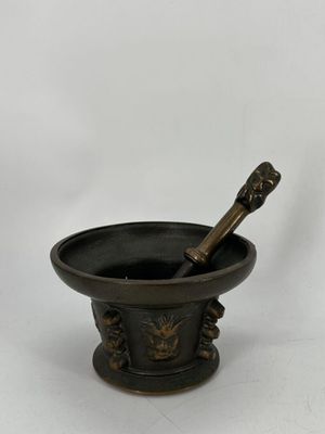 un mortier noir contenant un pilon en bois, sur fond blanc