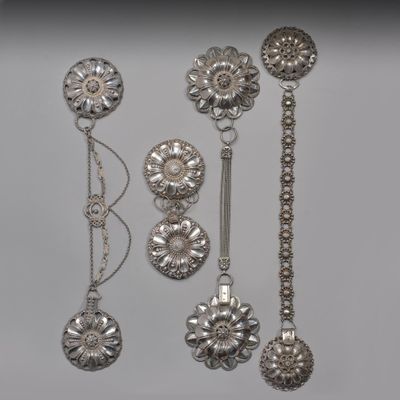 cinq cuillères en argent et une paire de boucles d'oreilles posées sur une table