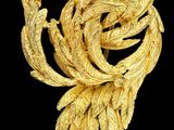 une image représentant une broche en or ornée de feuilles sur fond noir