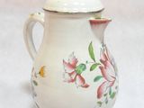 a small white tea pot with a flower design on it