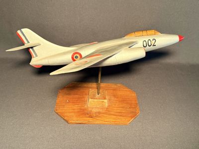 une maquette d'avion de chasse posée sur un socle en bois
