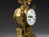 a gold clock with a bird on top of it