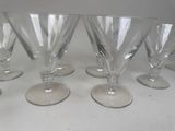 six clear wine glasses lined up on a white table