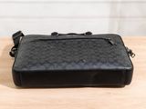 black coach messenger bag on table with white wall in background