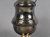 a silver vase with a spoon on top of it