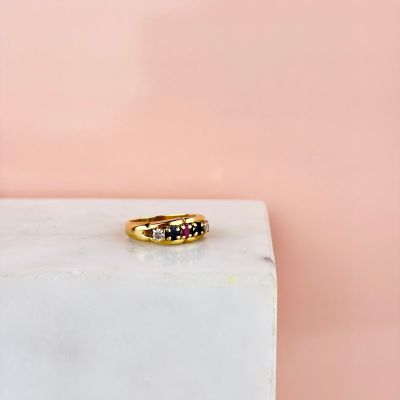 une bague en or sertie de pierres noires et blanches, posée sur un bloc de marbre